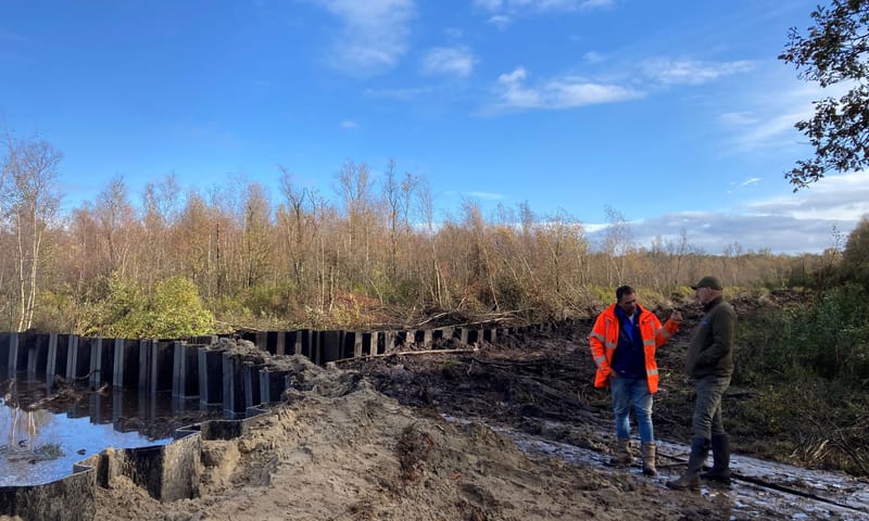 Boswachter en aannemer bespreken samen in het veen het plaatsen van de damwanden Boswachter en aannemer bespreken samen in het veen het plaatsen van de damwanden