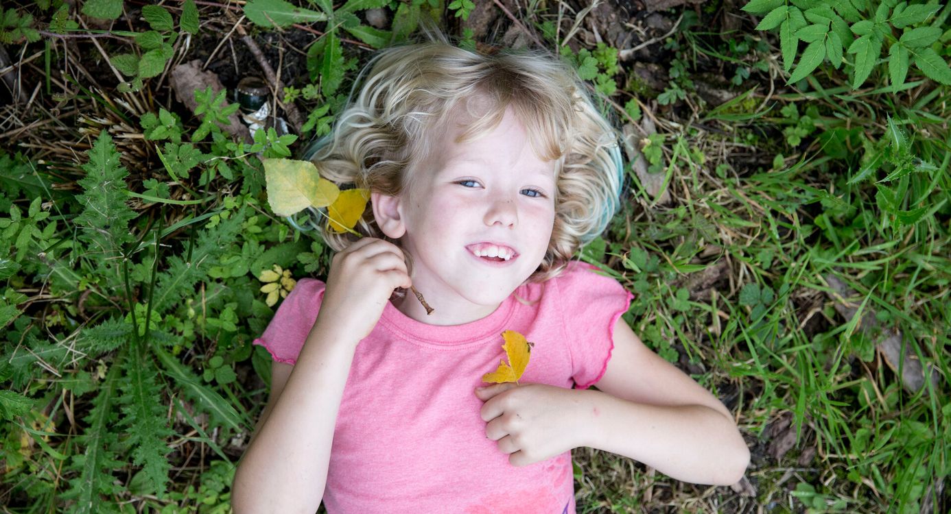 Blij kind ligt op de grond in het groen