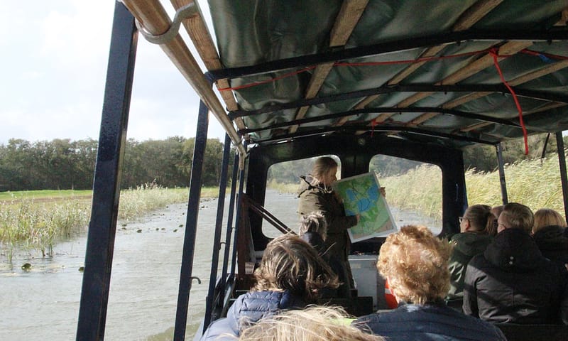 Gids geeft uitleg aan bezoekers in de boot op het Naardermeer