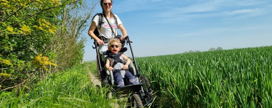 Wandelaar duwt kind in wagen over semi-verhard pad