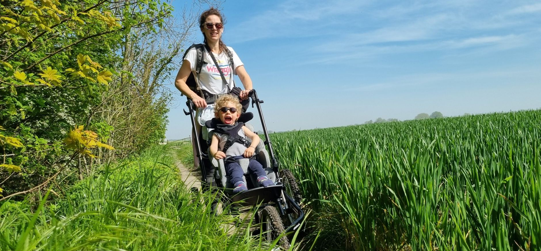Wandelaar duwt kind in wagen over semi-verhard pad