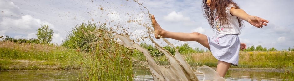 Kinderen spelen bij water op een OERRR-speelplek