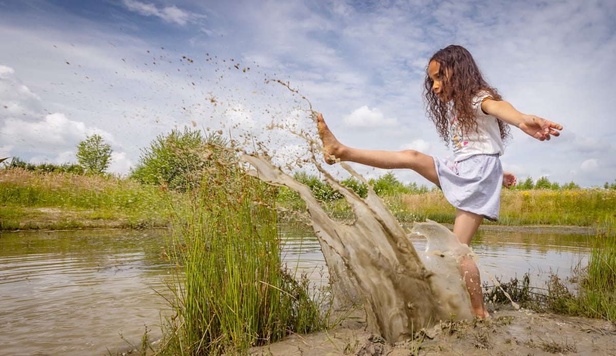 Kinderen spelen bij water op een OERRR-speelplek