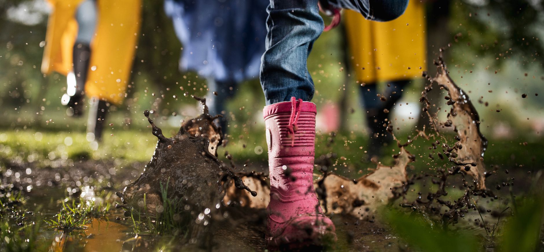 Kinderen met regenlaarzen spelen buiten na een regenbui.