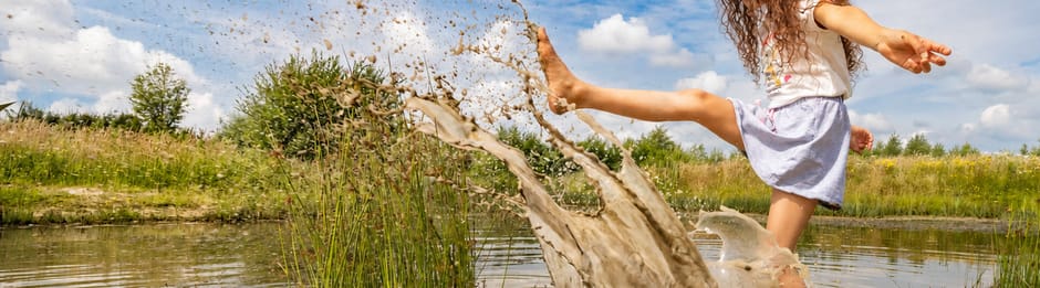 Kinderen spelen bij water op een OERRR-speelplek