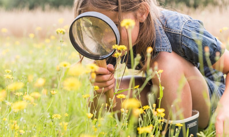 Meisje met loep en bloemen