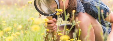 Meisje met loep en bloemen