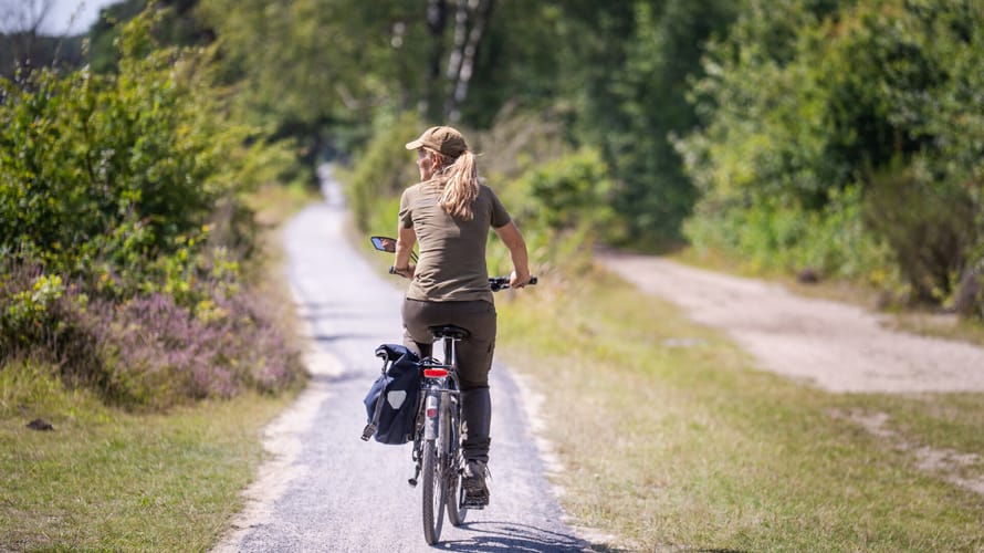 Vrouw fietst op fietspad door het Drentse landschap
