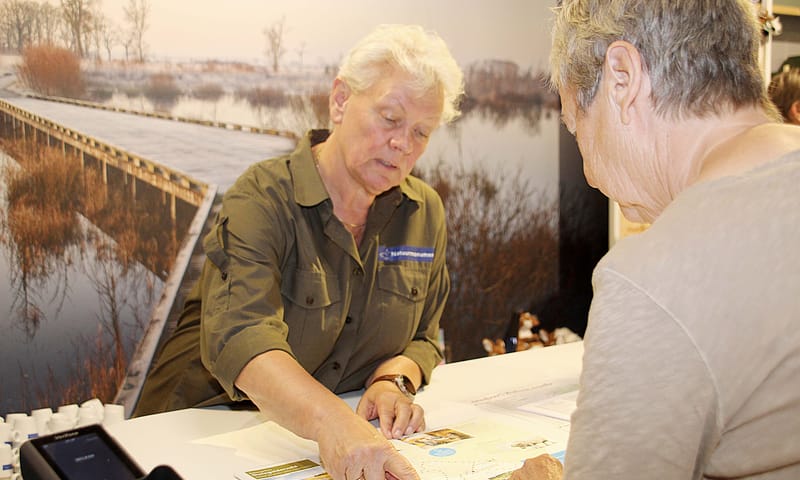 Vrijwilliger Tanja helpt een bezoeker van het Bezoekerscentrum Vrijwilliger Tanja helpt een bezoeker van het Bezoekerscentrum