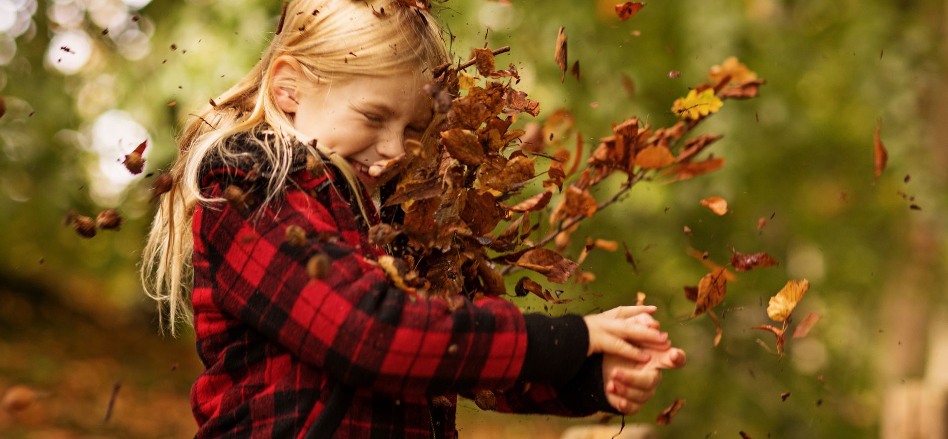 Kind gooit herfstbladeren in de lucht