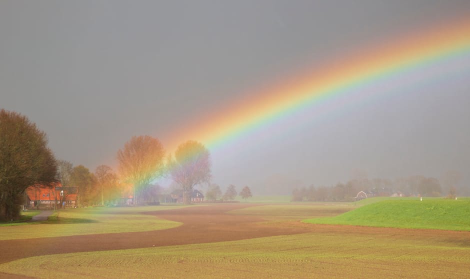 Buienweer 24 maart 2023. En dan verschuift het licht naar zacht paarsblauw. In een prachtige aanvulling op de kleuren in de voorgrond verschijnt de regenboog.