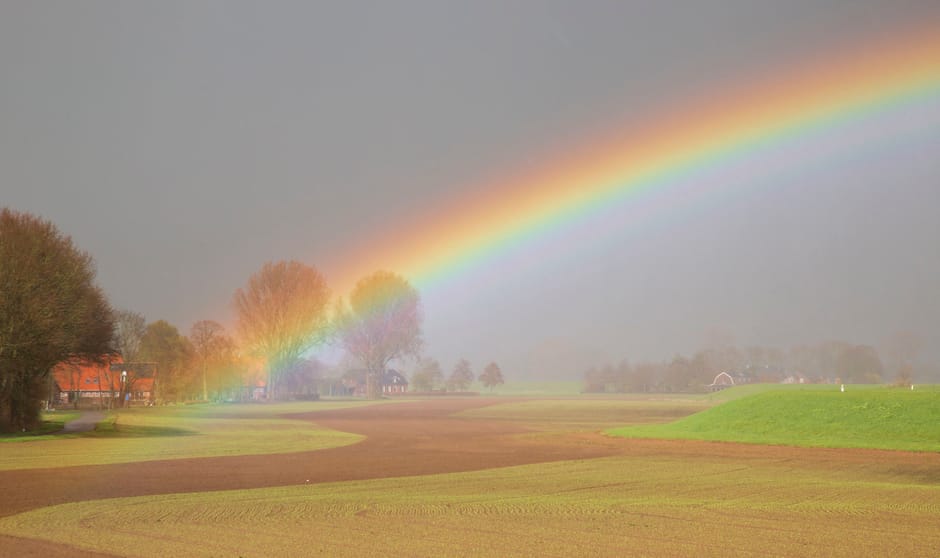 Buienweer 24 maart 2023. En dan verschuift het licht naar zacht paarsblauw. In een prachtige aanvulling op de kleuren in de voorgrond verschijnt de regenboog.