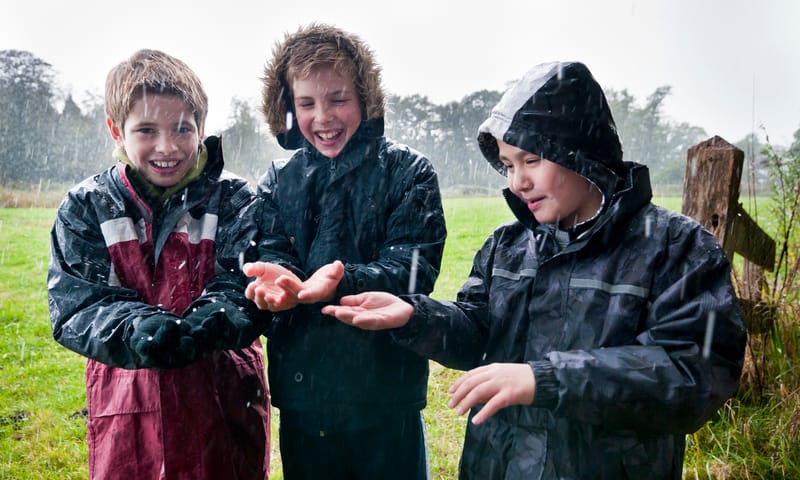 Kinderen laten regen op hun handen neerkomen