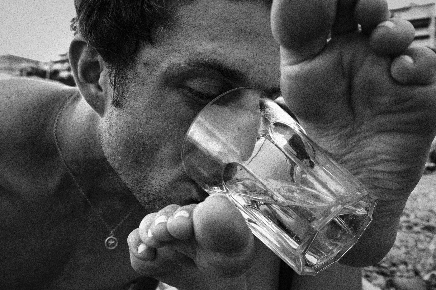 man drinking from cup held by woman's feet