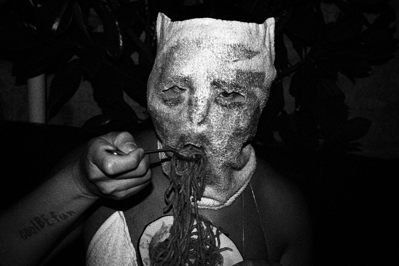 a man with a mask eating pasta