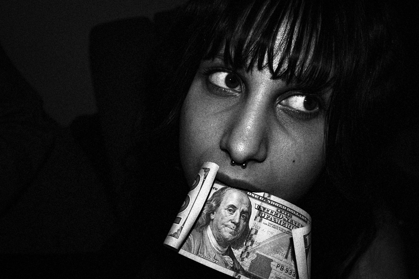 woman with 100 dollar bill in her mouth