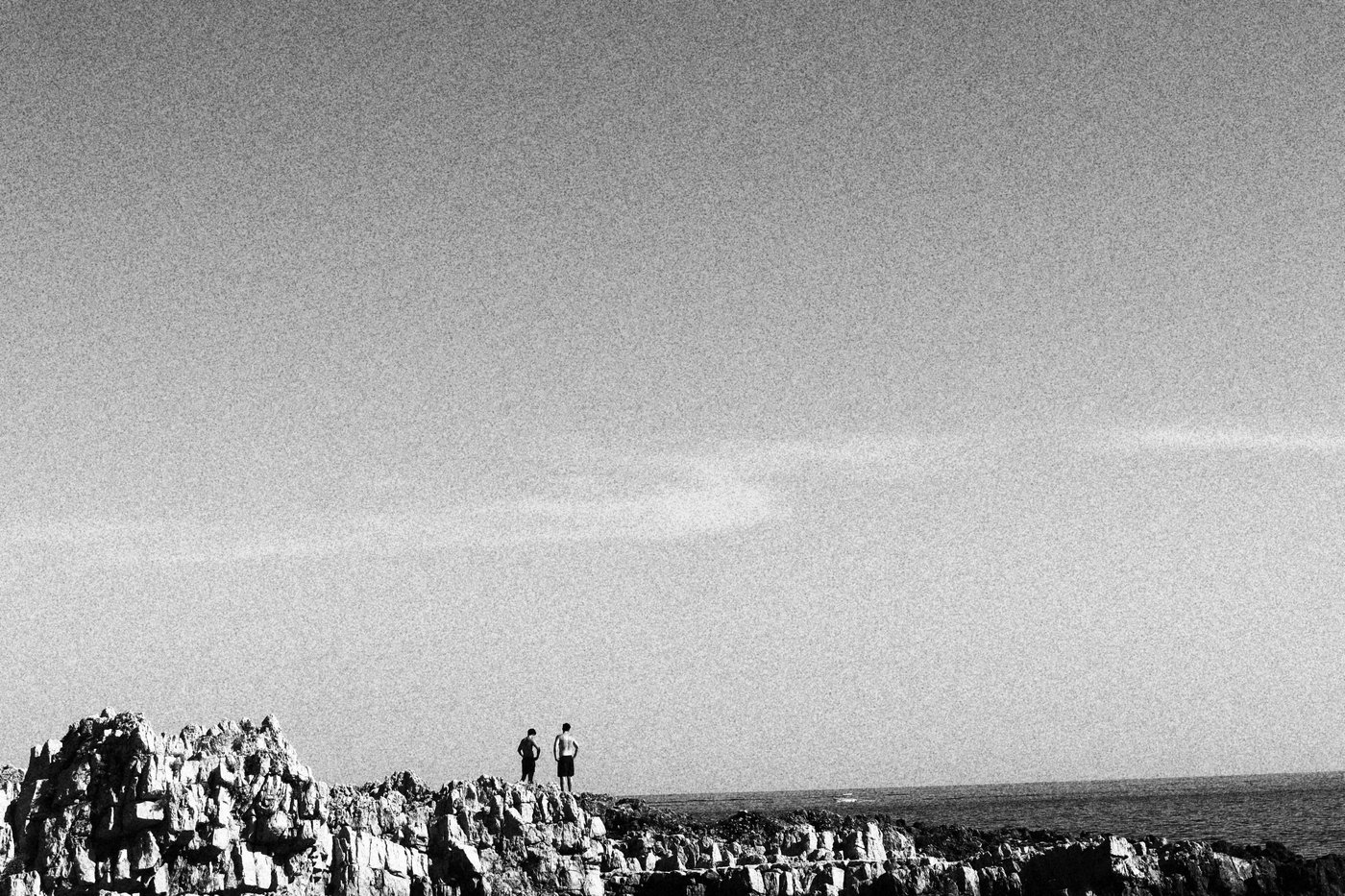 two men looking into the ocean on the rocks