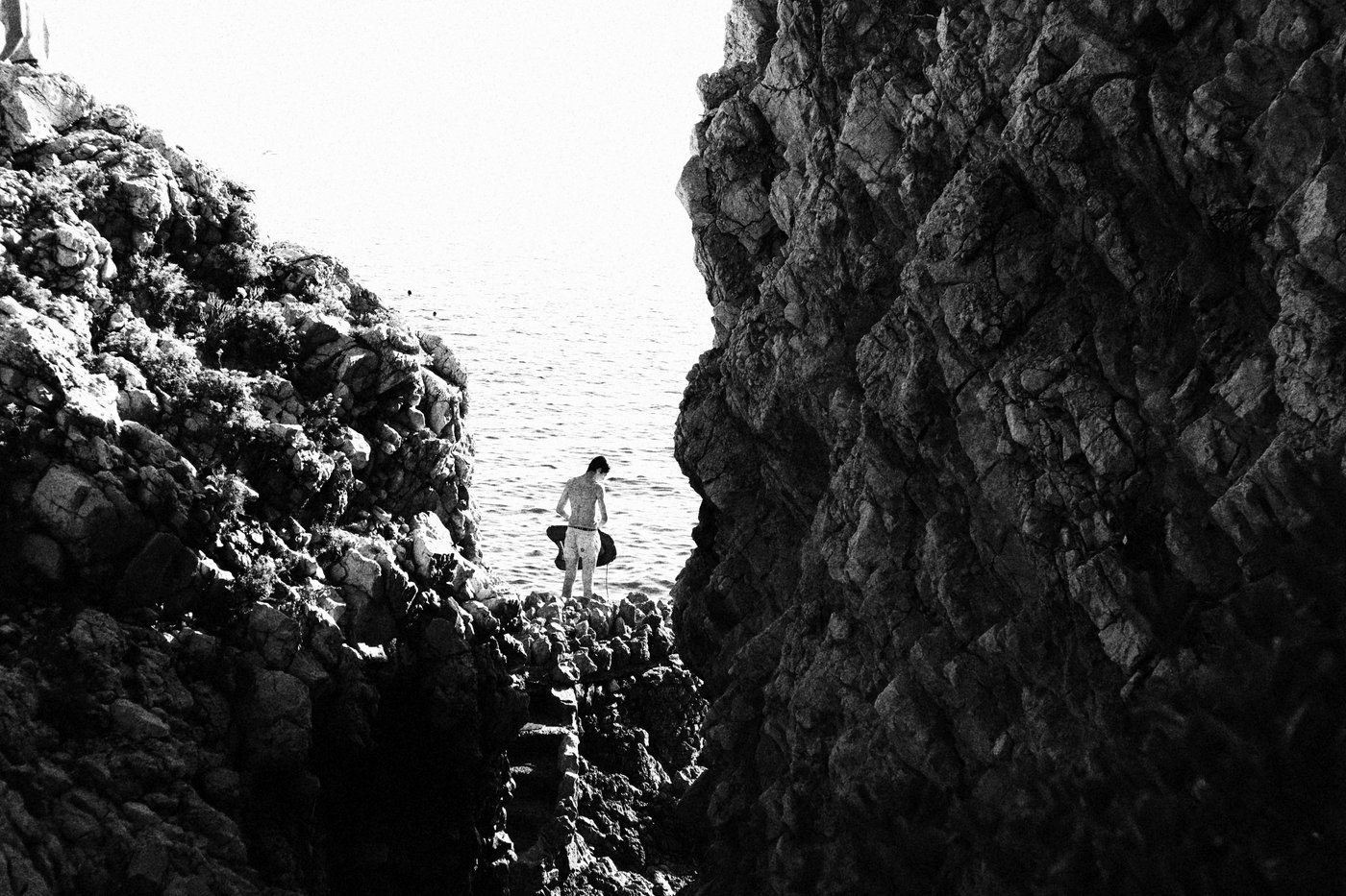 a man looking into the ocean between two rocks