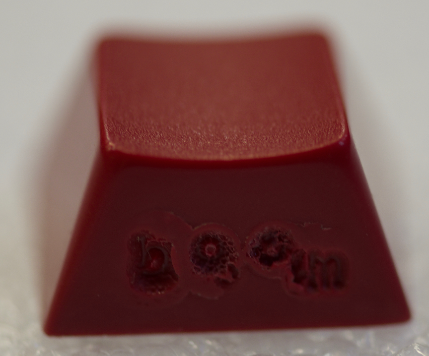 Proto Esc GMK Plum Color sample with "boom" melted in