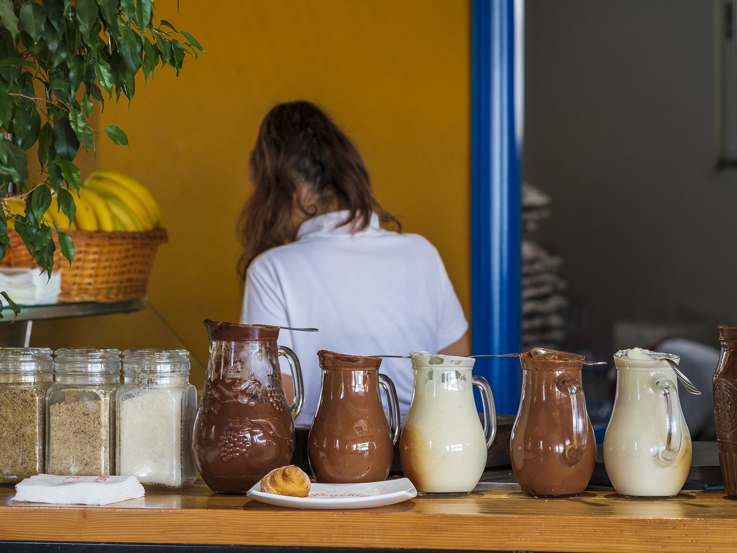 Jugs and a pastry on the counter at a cafe in Durres