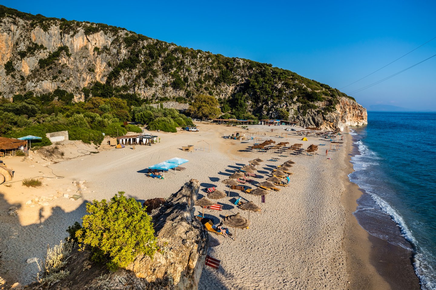 People relaxing under umbrellas on the sandy Gjipe Beach near Himare, Albania