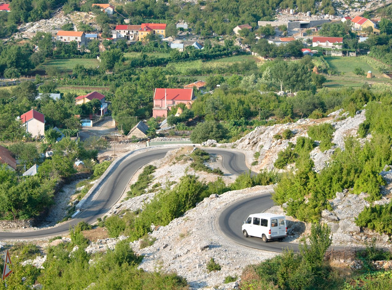 White minibus on the winding road from Razem to Shkoder, Albania