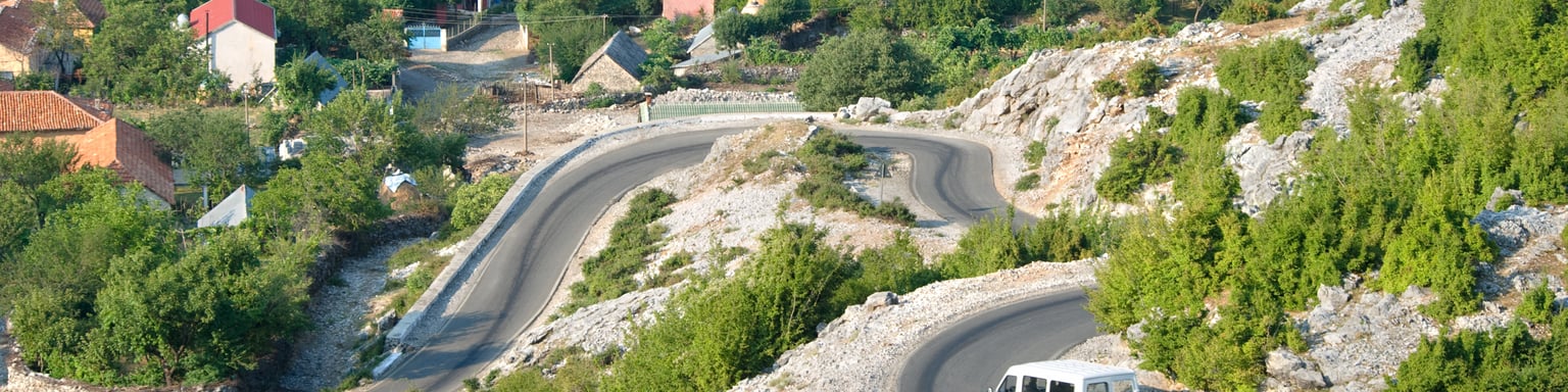 White minibus on the winding road from Razem to Shkoder, Albania