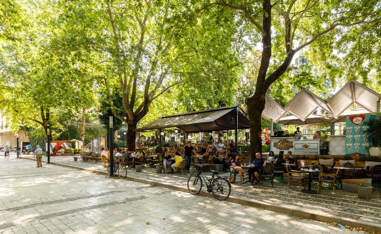 People sitting under trees at an outdoor cafe in Tirana, Albania
