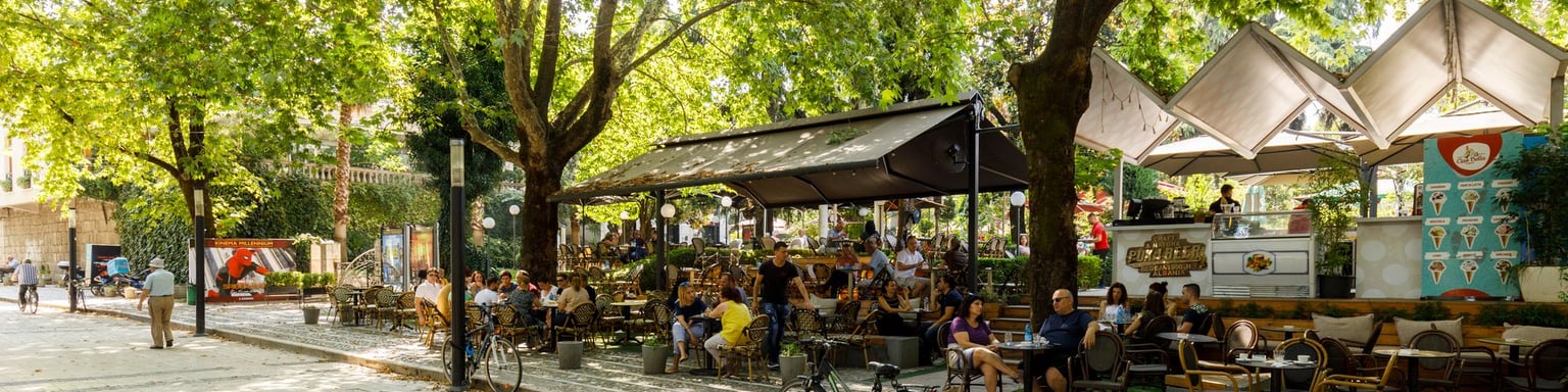People sitting under trees at an outdoor cafe in Tirana, Albania
