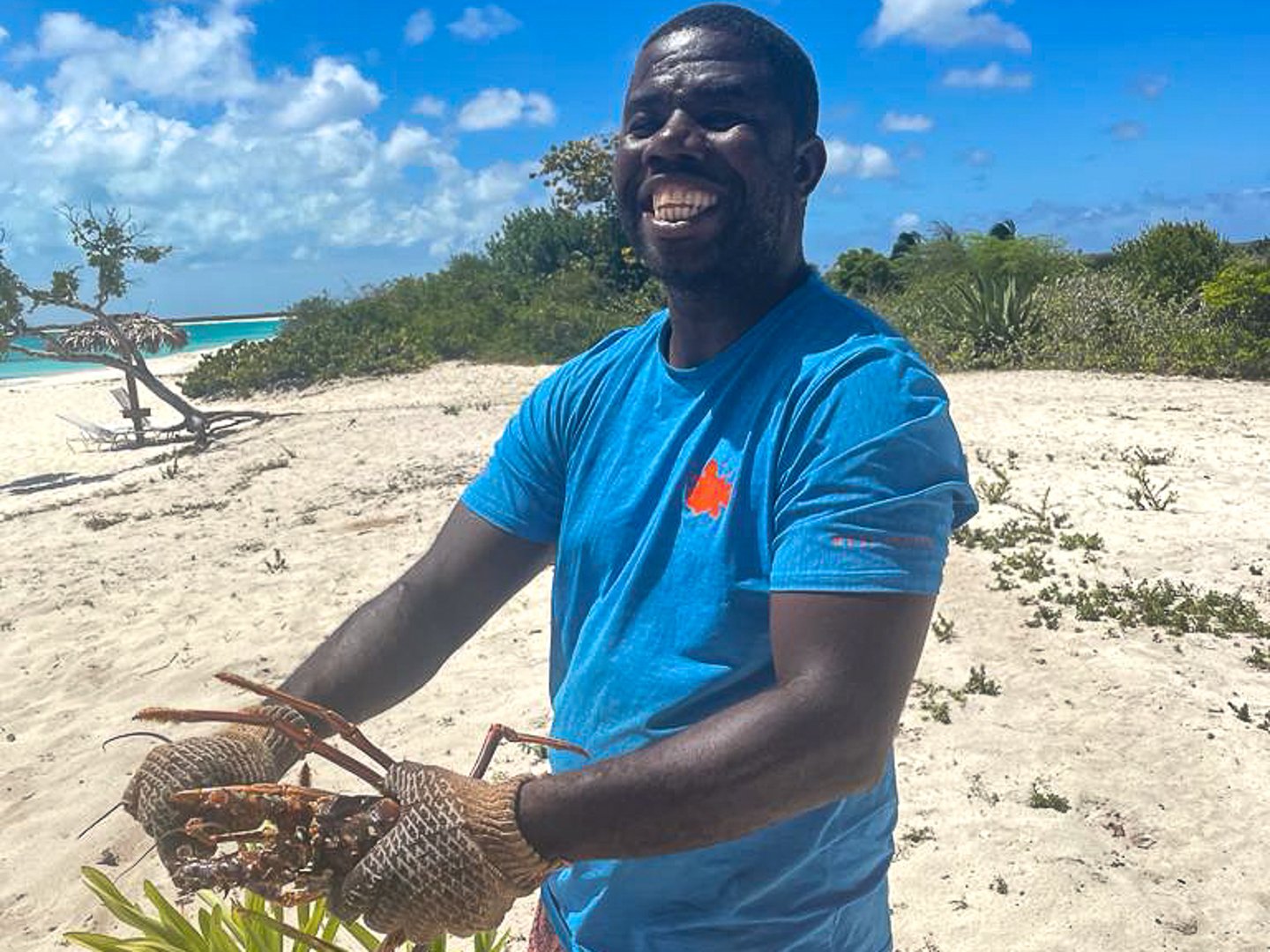 A man with a lobster on a beach in Barbuda