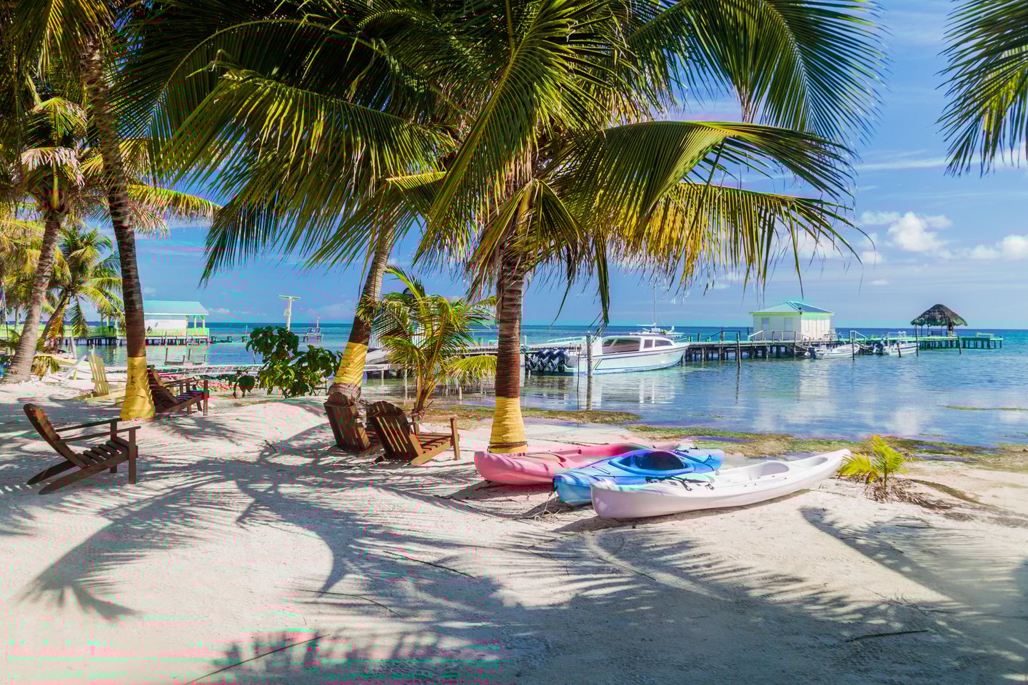 Kayaks and chairs on the beach under palm trees in Caye Caulker, Belize