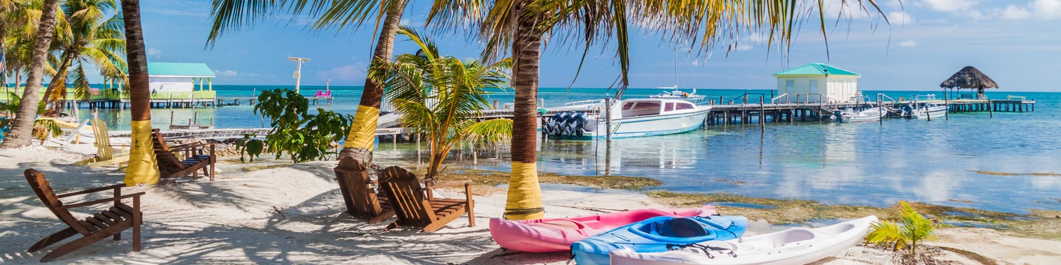 Kayaks and chairs on the beach under palm trees in Caye Caulker, Belize