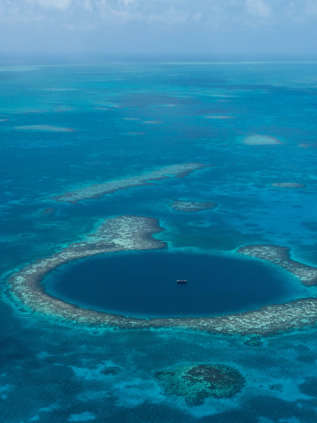 An aerial view of a boat in the centre of Belize's Great Blue Hole
