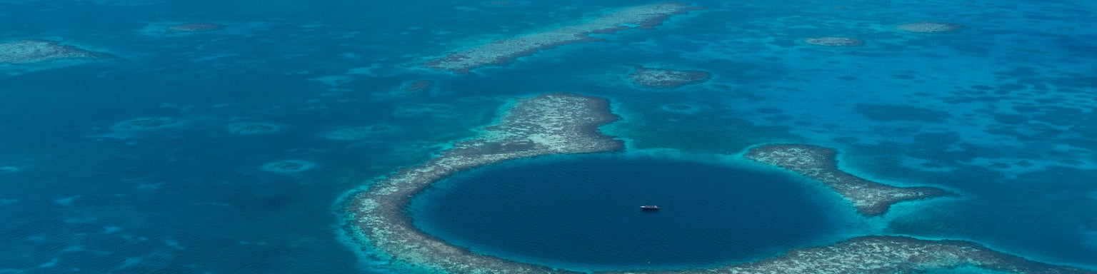 An aerial view of a boat in the centre of Belize's Great Blue Hole