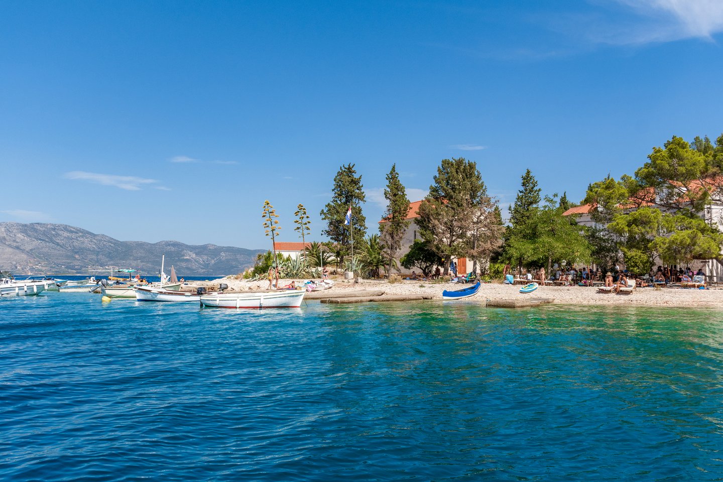 Boats and people on a beach on Vrnik Island in Croatia.