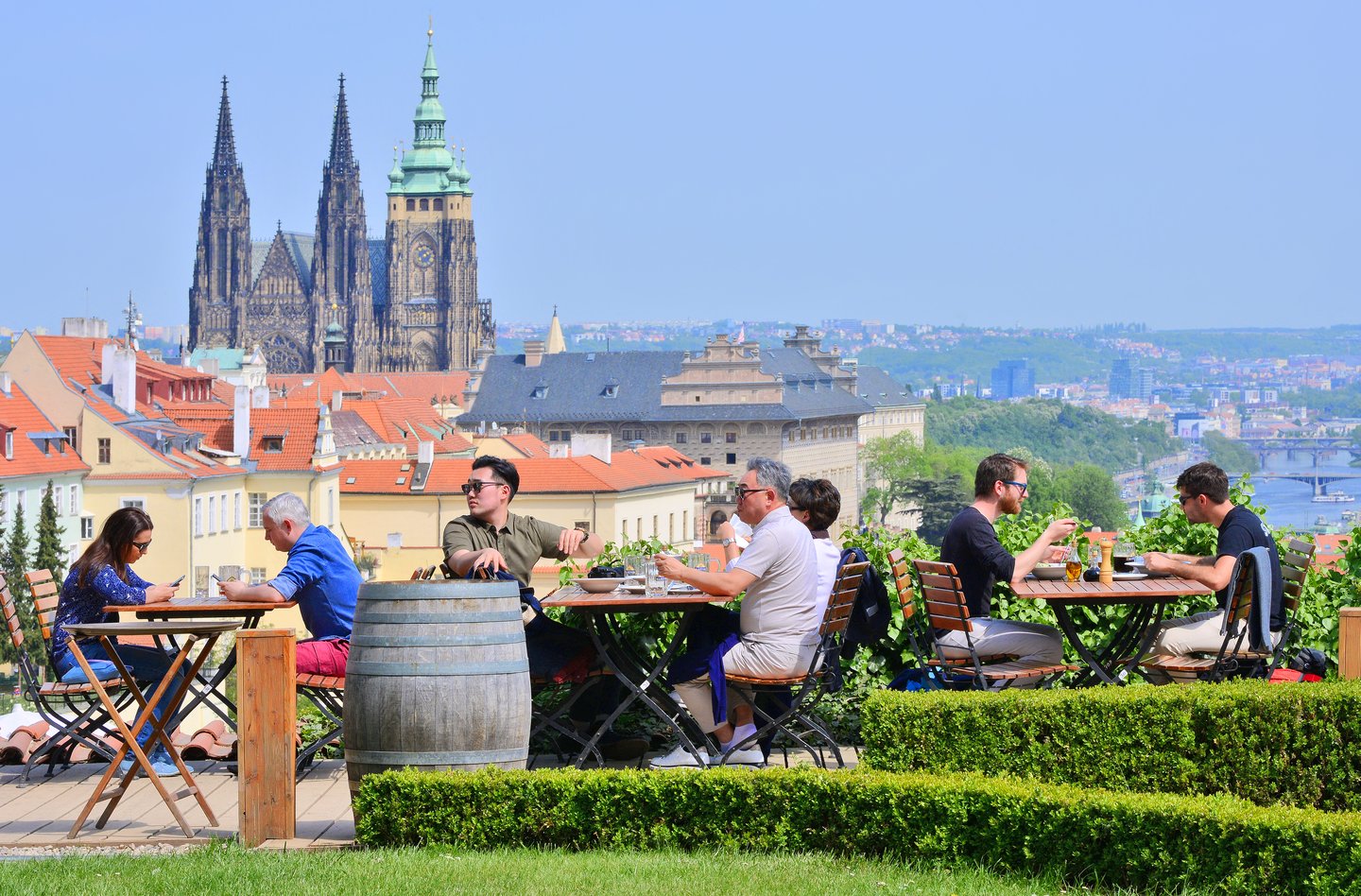 People sitting in a restaurant at the Strahov Monastery with views of Prague in the background 