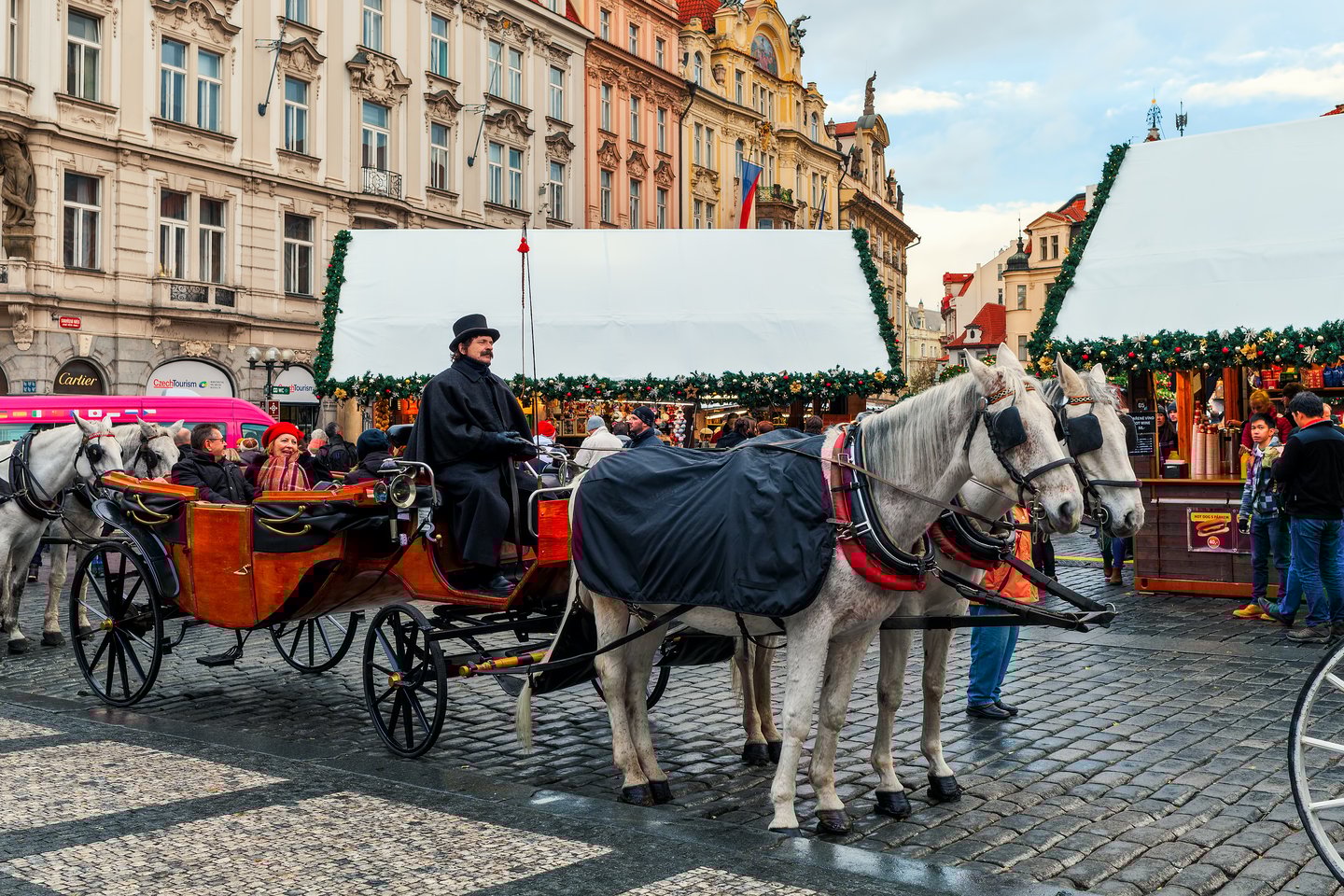 People in a horse-drawn carriage by the Christmas markets in Prague.