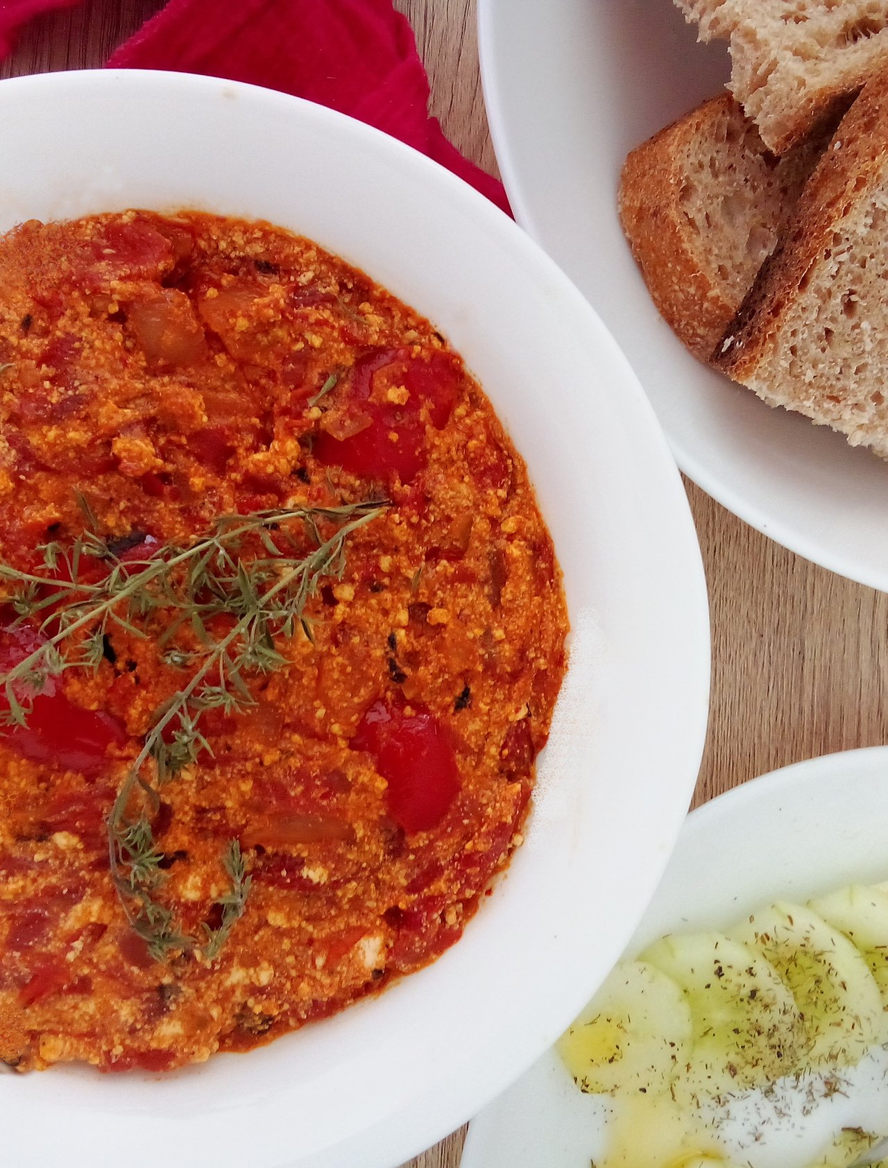 A bowl of Albanian fergese on a table with bread and a salad