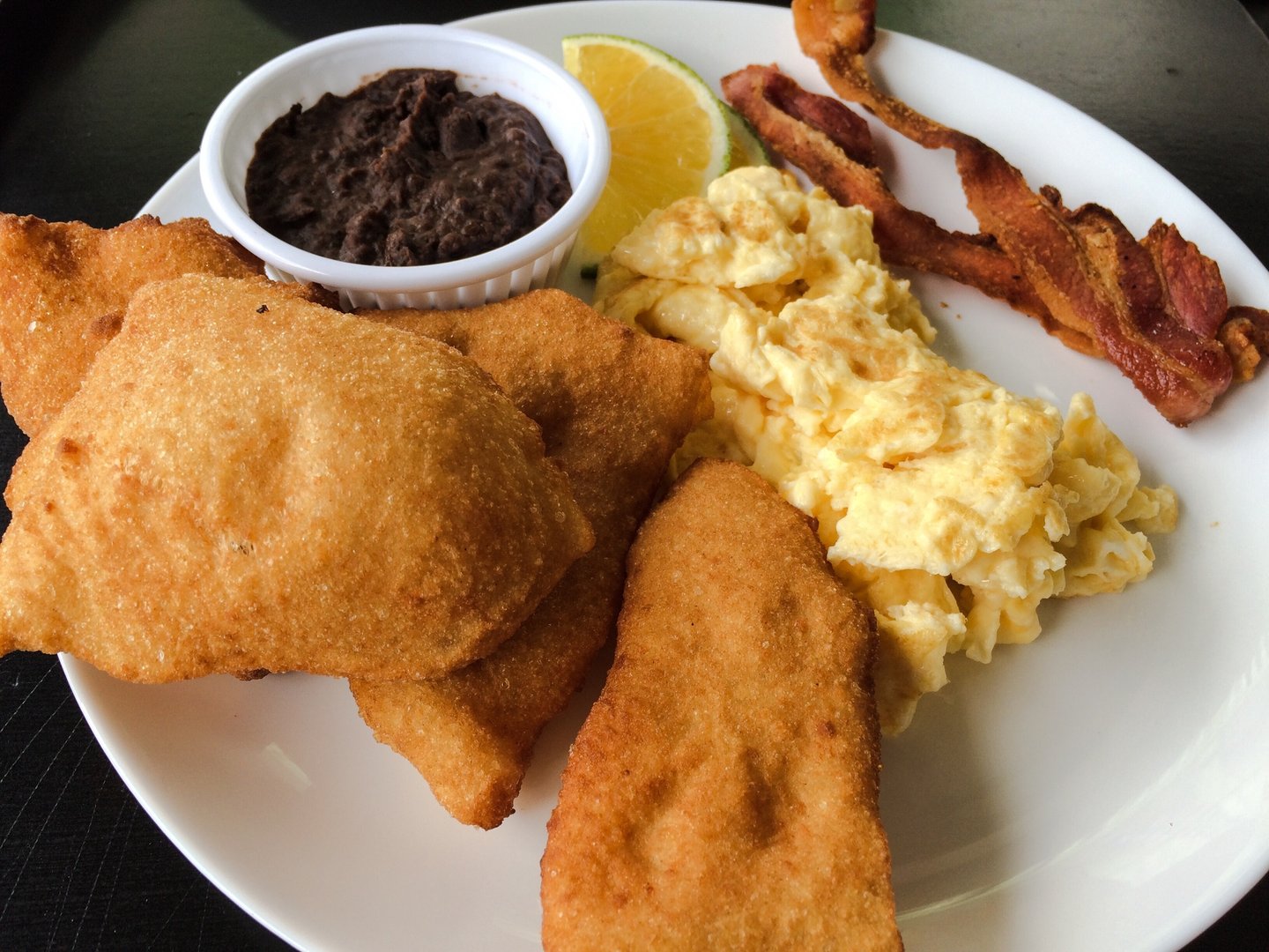 A Belizean-style breakfast with eggs, bacon and fry jacks