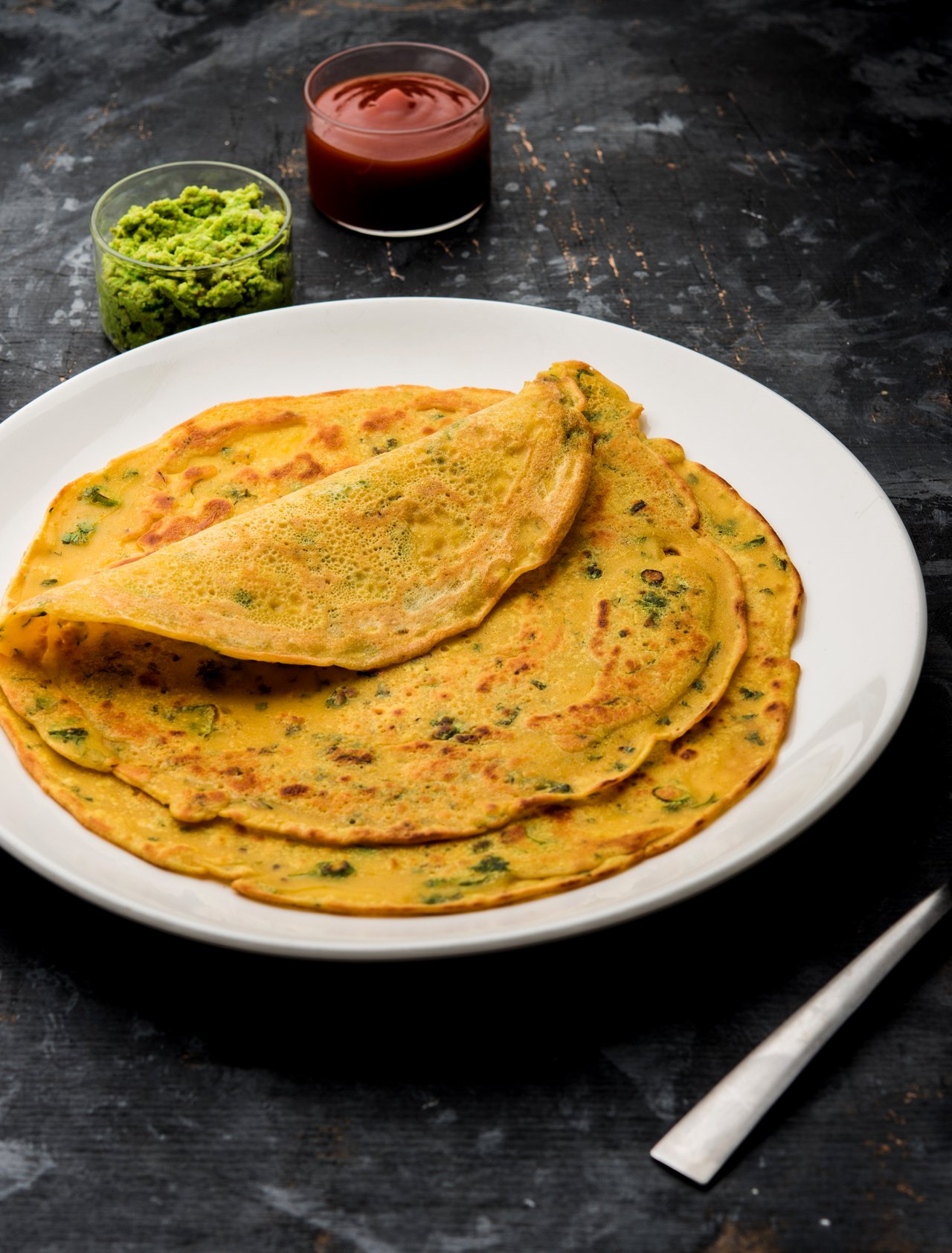 Besan chilla, a savoury pancake, served with sauces