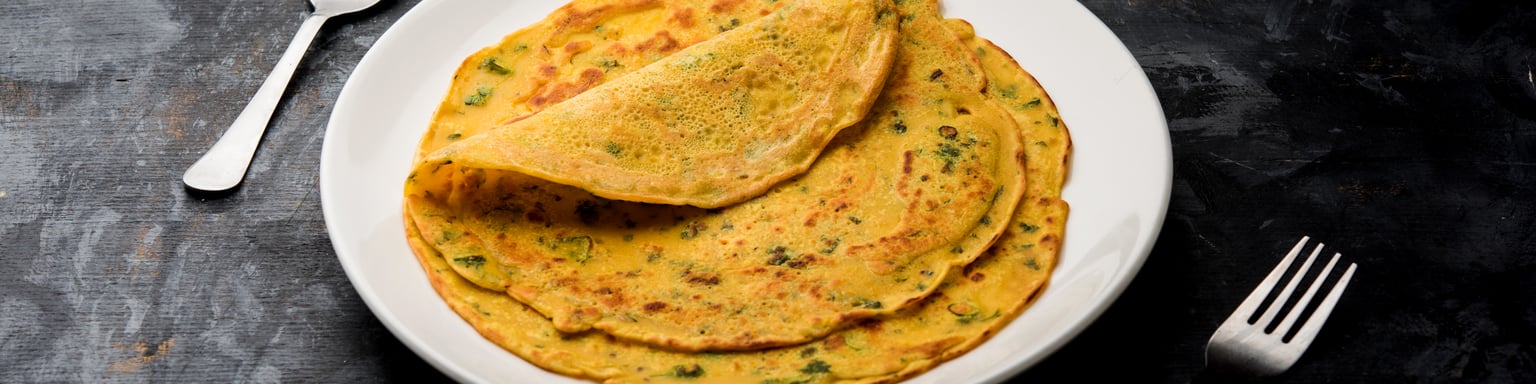 Besan chilla, a savoury pancake, served with sauces