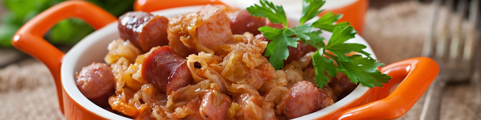 Bigos with sausage and bacon in a red dutch oven