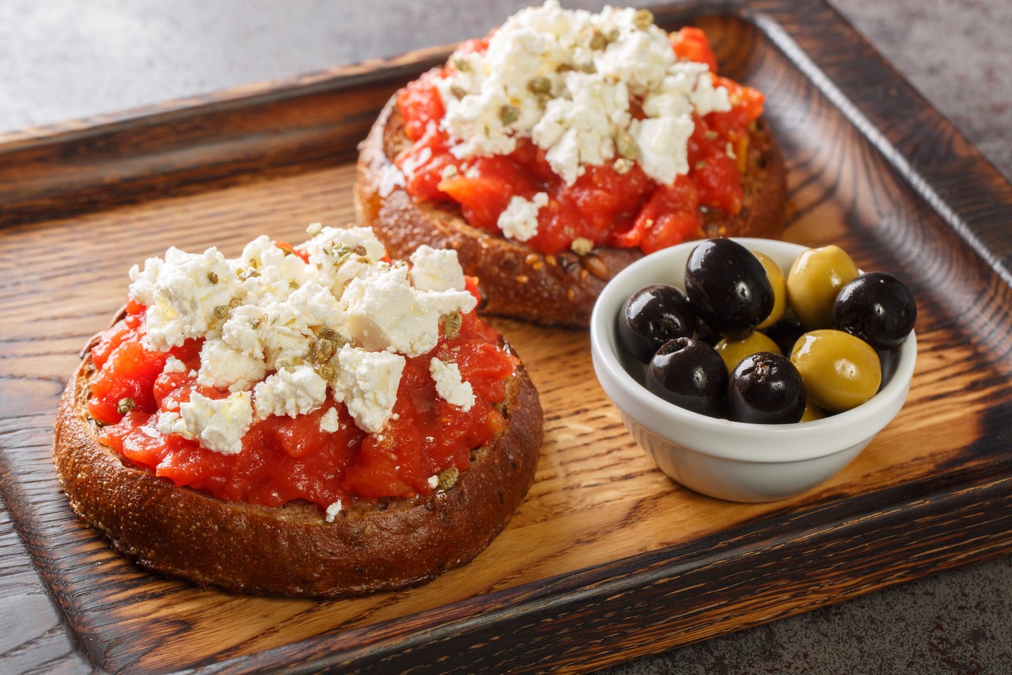 Cretan dakos, a barley rusk topped with juicy tomatoes, cheese and olive oil