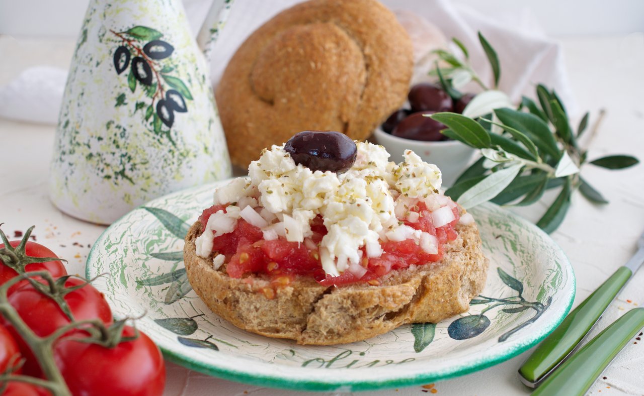 Dakos served with tomatoes and cheese on a pretty plate