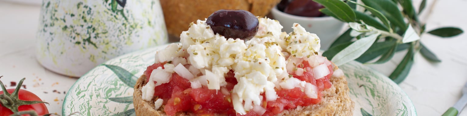 Dakos served with tomatoes and cheese on a pretty plate