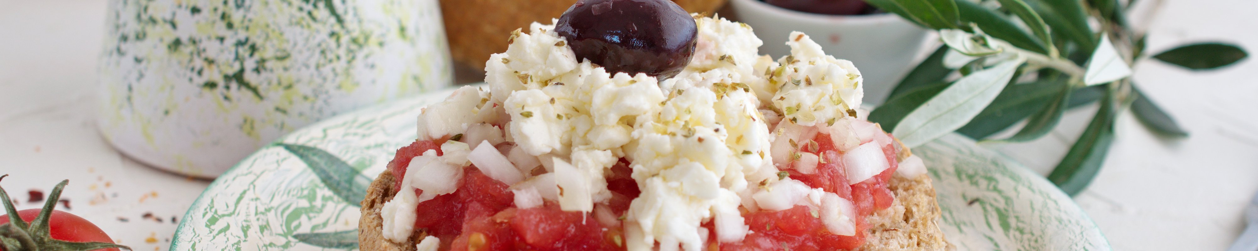 Dakos served with tomatoes and cheese on a pretty plate