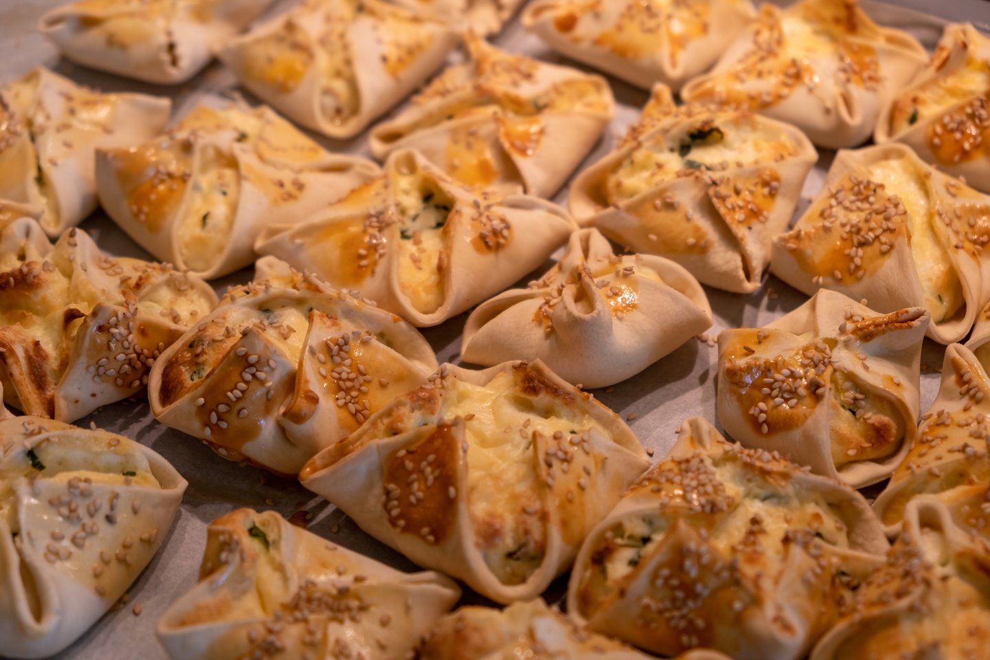 Kaltsounia, small pies filled with mizithra and drizzled with honey and sesame seeds