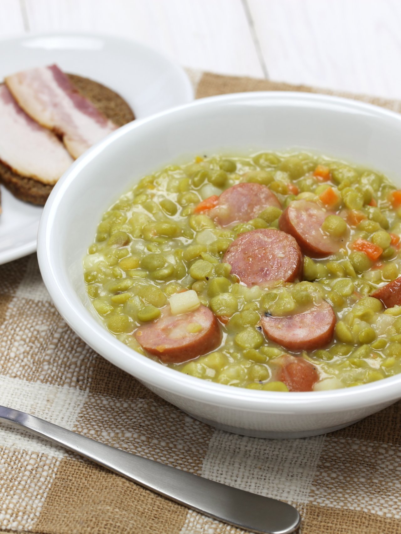 A bowl of erwtensoep with rye bread with bacon