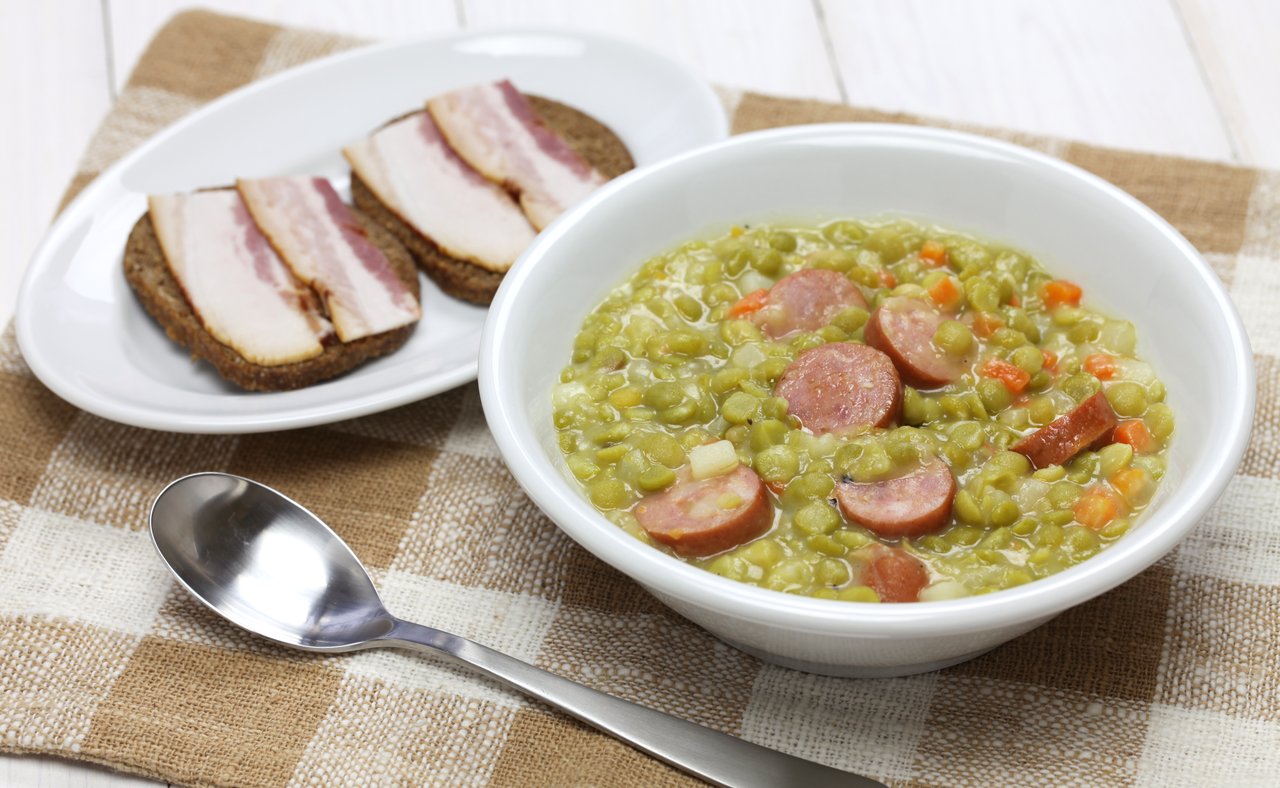 A bowl of erwtensoep with rye bread with bacon