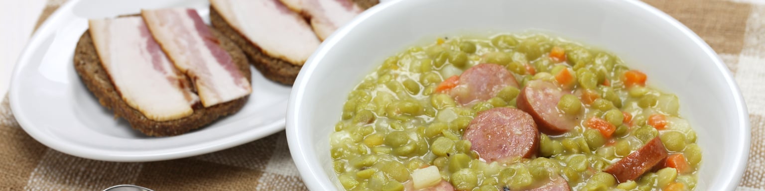 A bowl of erwtensoep with rye bread with bacon